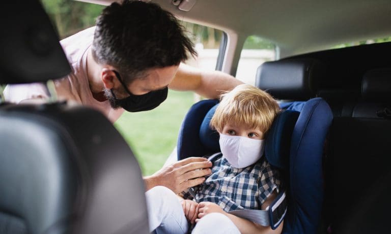 Kind mit Maske im Auto — halfpoint / depositphotos.com